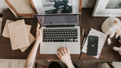 An aesthetic workspace featuring a laptop, smartphone, and stationery items from a top-down view.